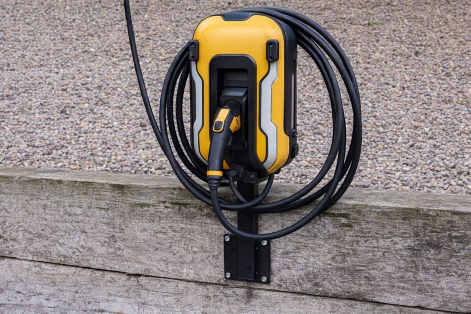 En gul och svart Zaptec laddbox monterad på en trävägg utomhus.