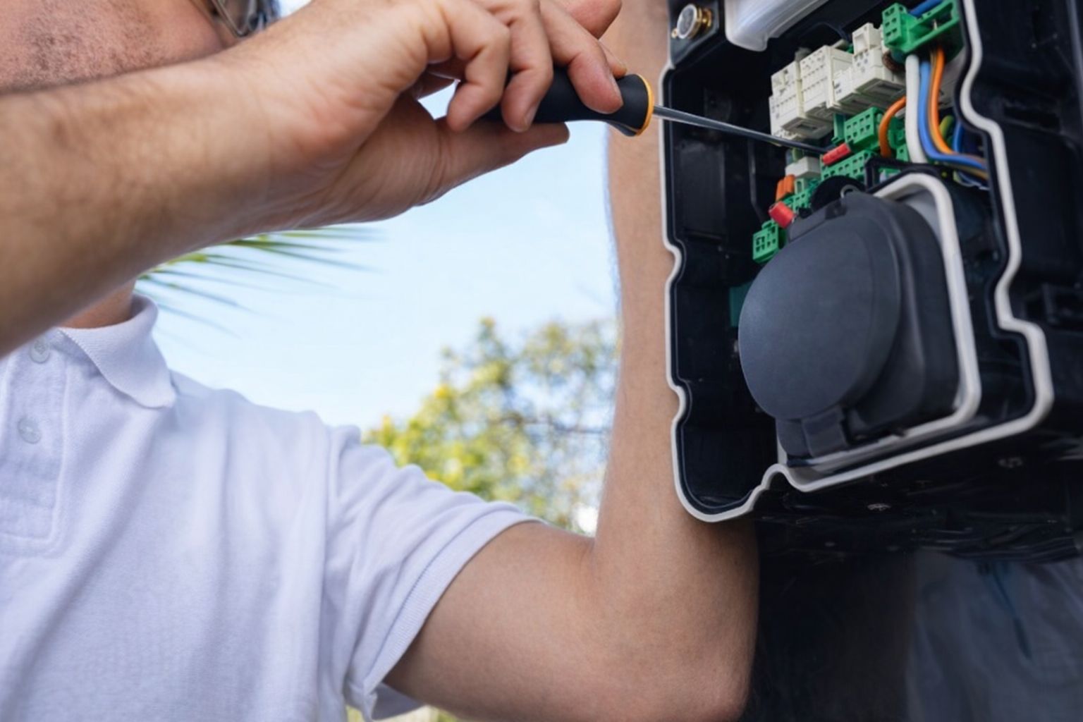 En tekniker installerar en Zaptec laddbox med en skruvmejsel.