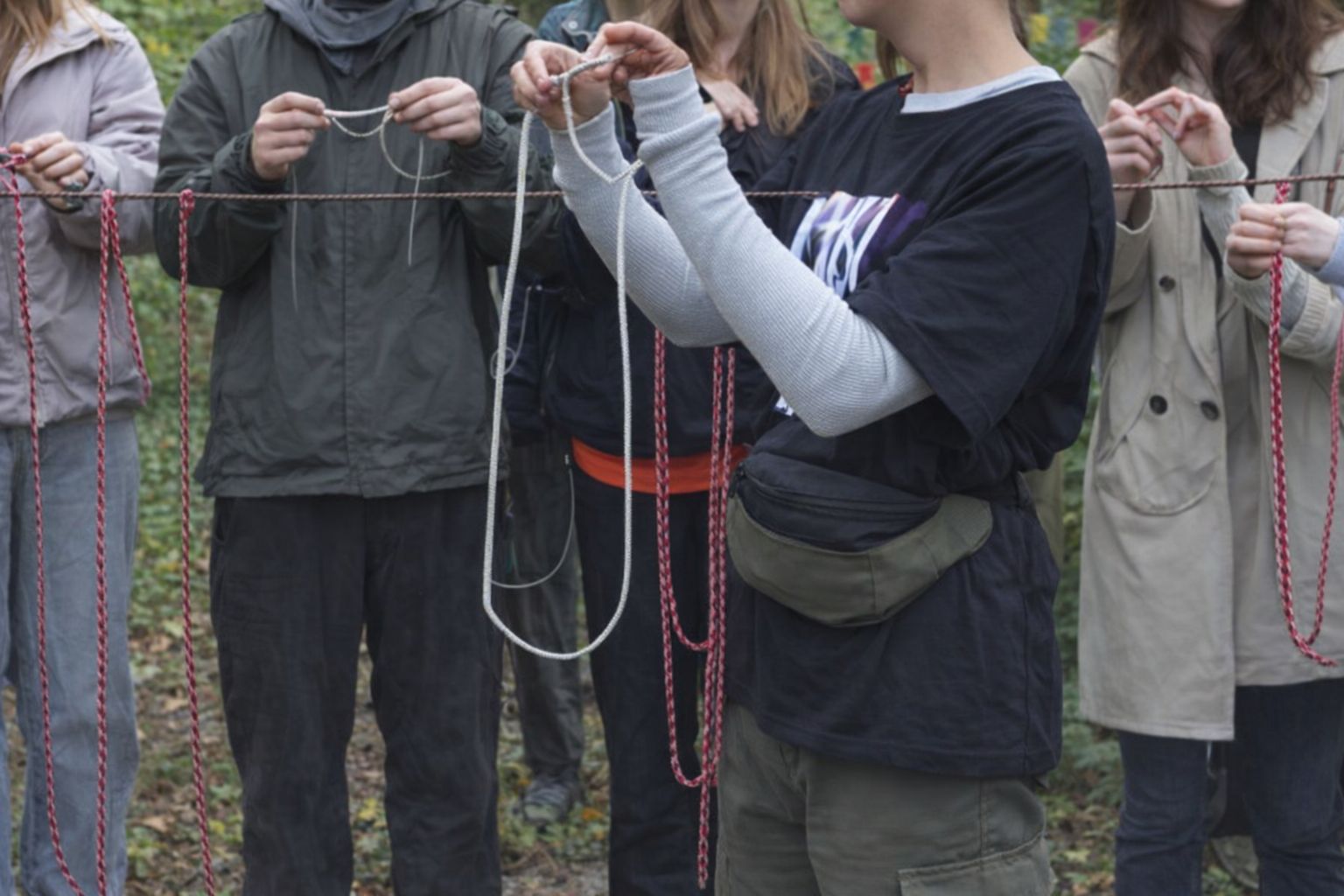 Elever i praktiska jackor deltar i en samarbetsövning utomhus.