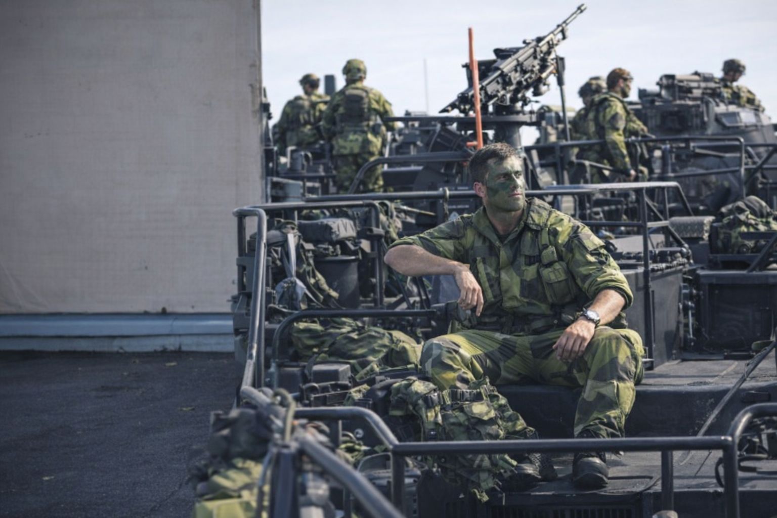 Svenska soldater i kamouflageuniform på ett militärfordon med vapenutrustning.